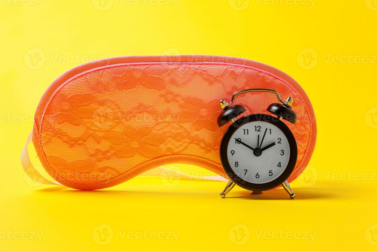 Sleeping eye mask, alarm clock isolated on yellow colourful trendy modern fashion background. Do not disturb me, let me sleep. Rest, good night, siesta, insomnia, relaxation, tired, travel concept. photo