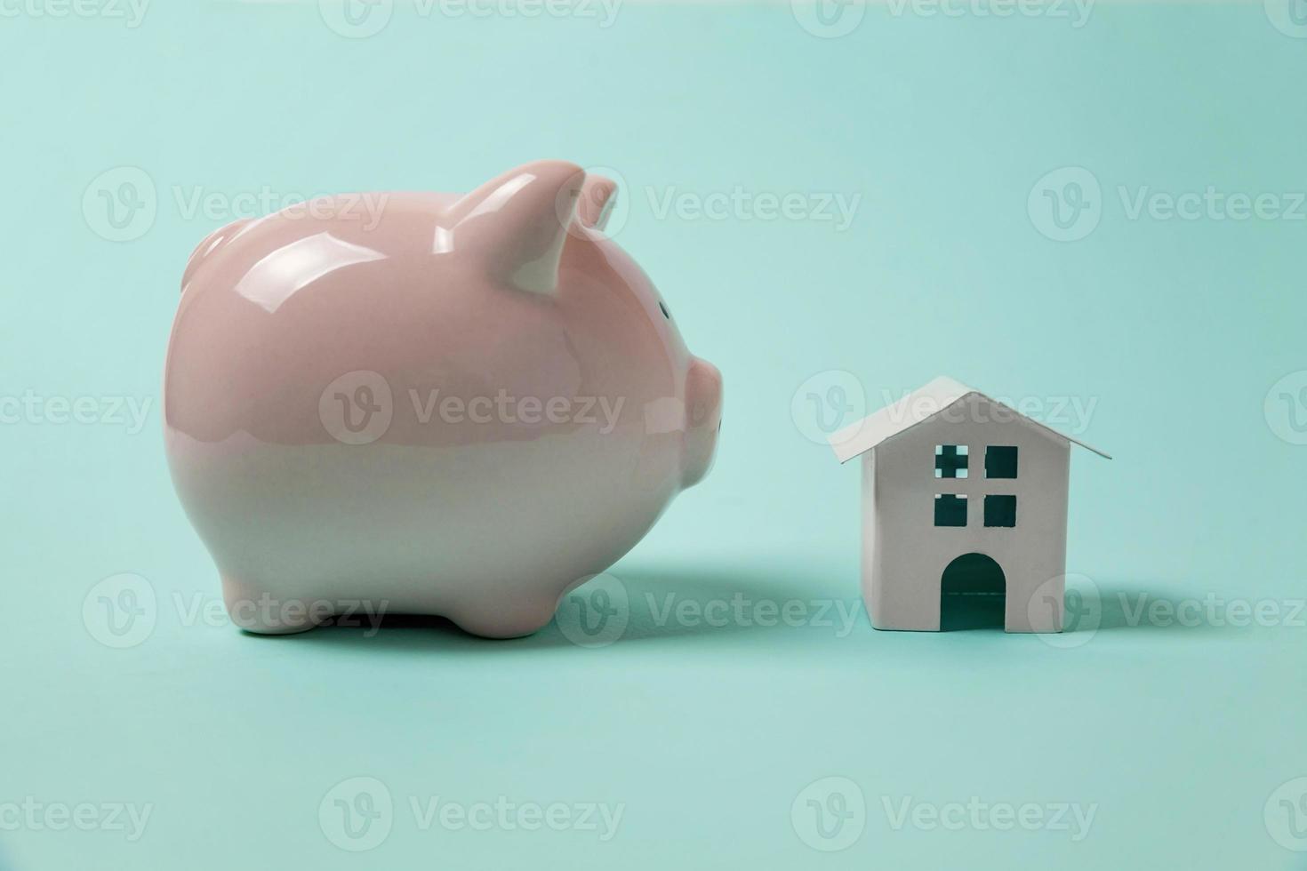Simply design with miniature toy house, piggy bank isolated isolated on blue pastel colourful trendy background. Mortgage property insurance dream home banking investment loan concept. Copy space. photo