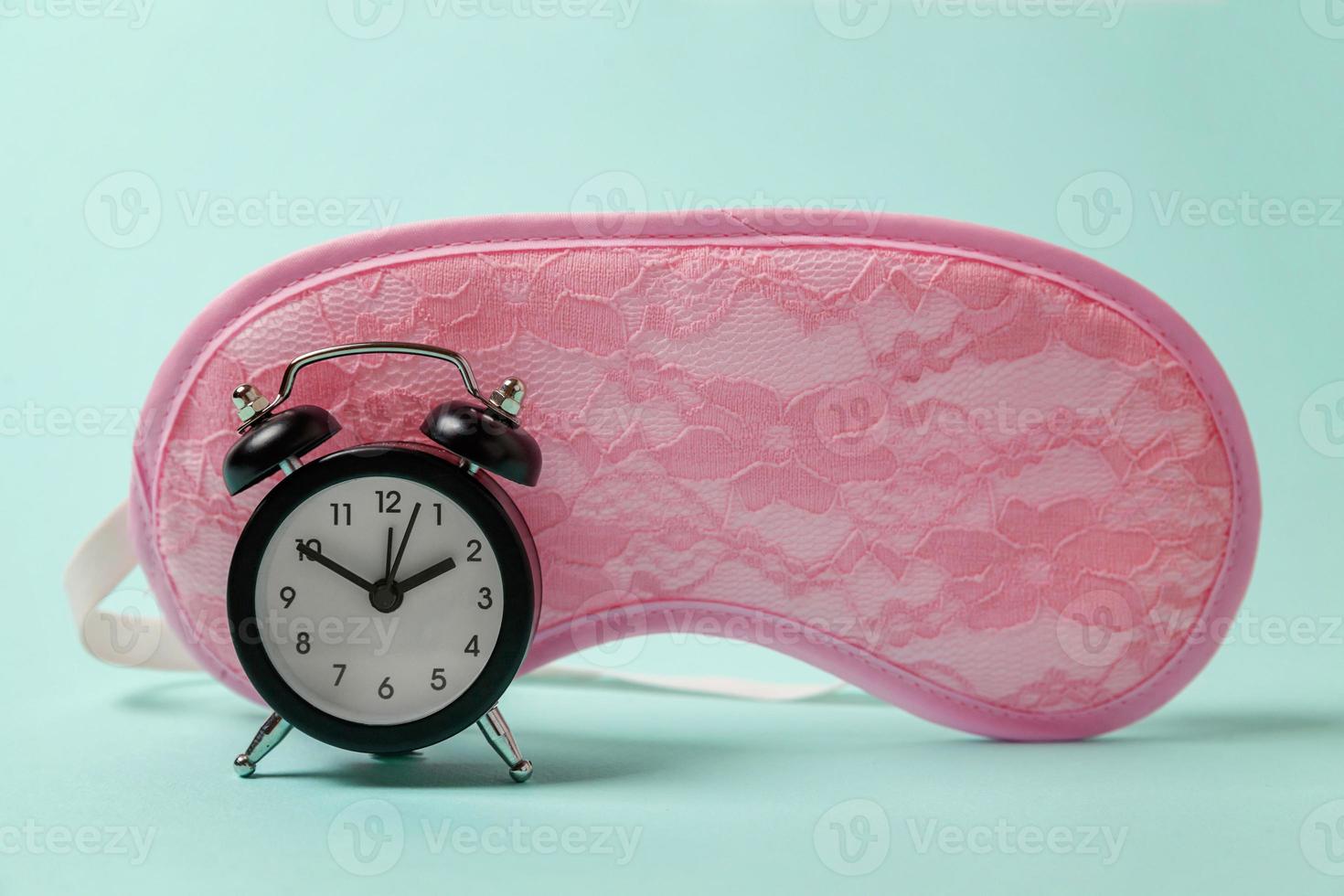 Sleeping eye mask, alarm clock isolated on blue pastel colourful trendy background. Do not disturb me, let me sleep. Rest, good night, siesta, insomnia, relaxation, tired, travel concept. photo