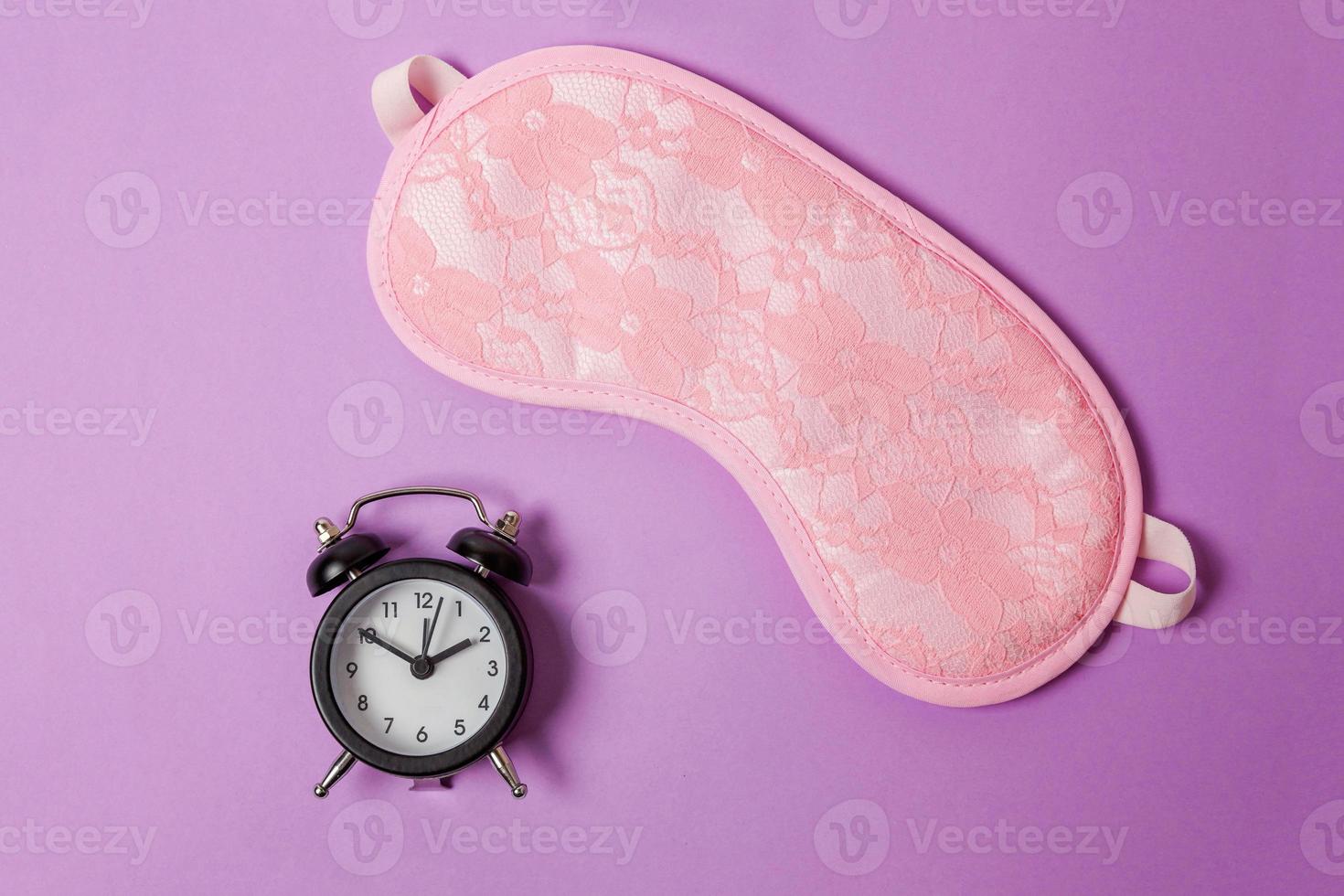 Sleeping eye mask, alarm clock isolated on purple violet pastel colourful trendy background. Do not disturb me, let me sleep. Rest, good night, siesta, insomnia, relaxation, tired, travel concept. photo