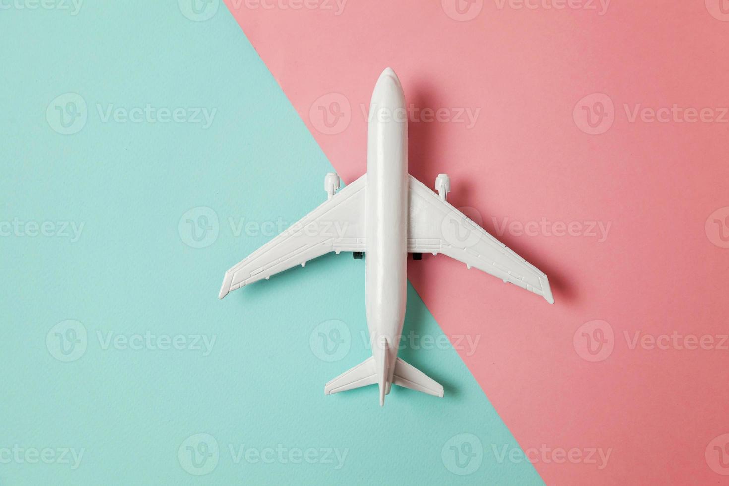 modelo de juguete en miniatura de diseño simplemente plano sobre fondo geométrico de moda de papel de colores pastel azul y rosa. viaje en avión vacaciones verano fin de semana aventura en el mar concepto de viaje. foto