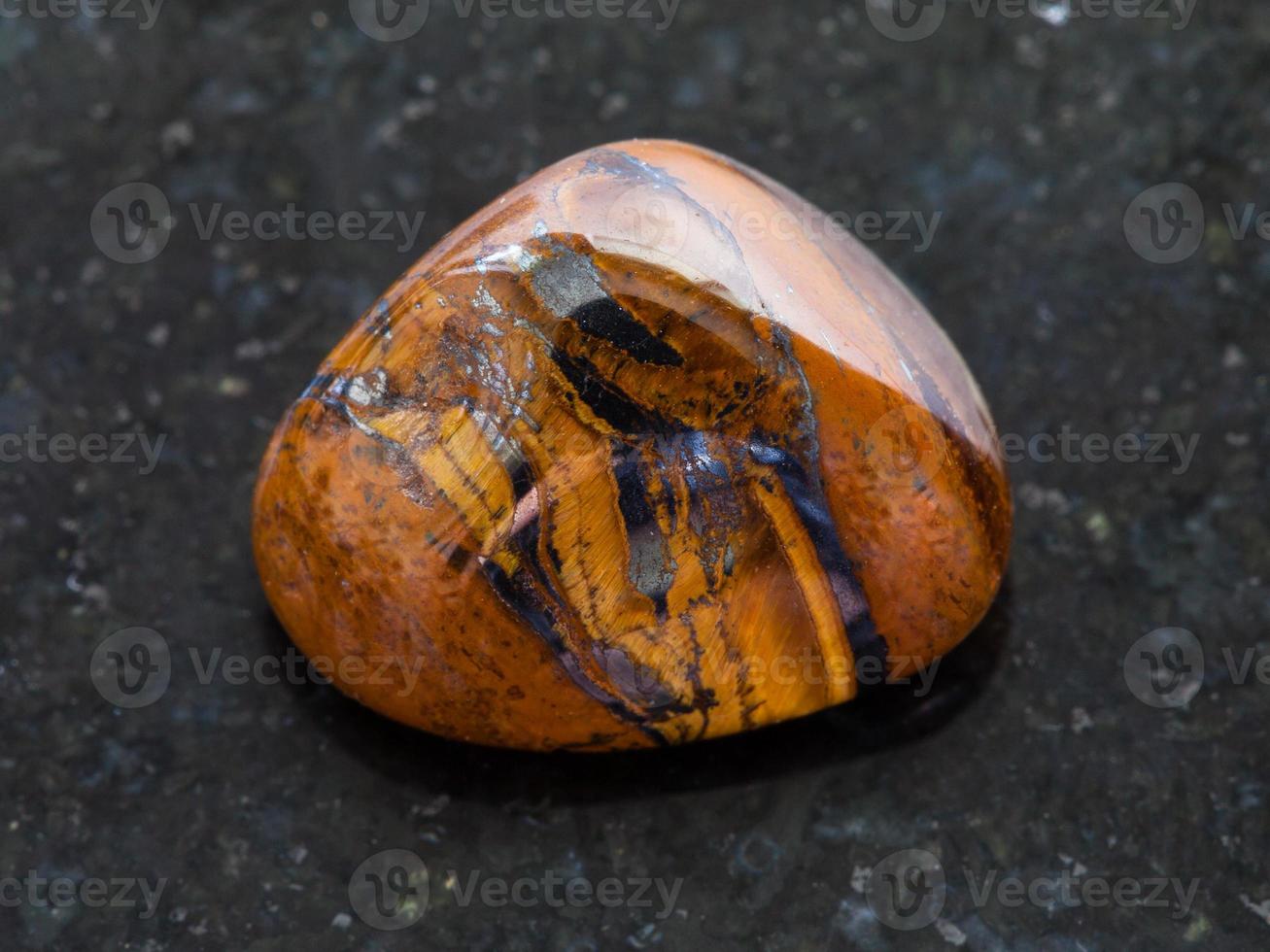 polished tigers eye gemstone on dark background photo