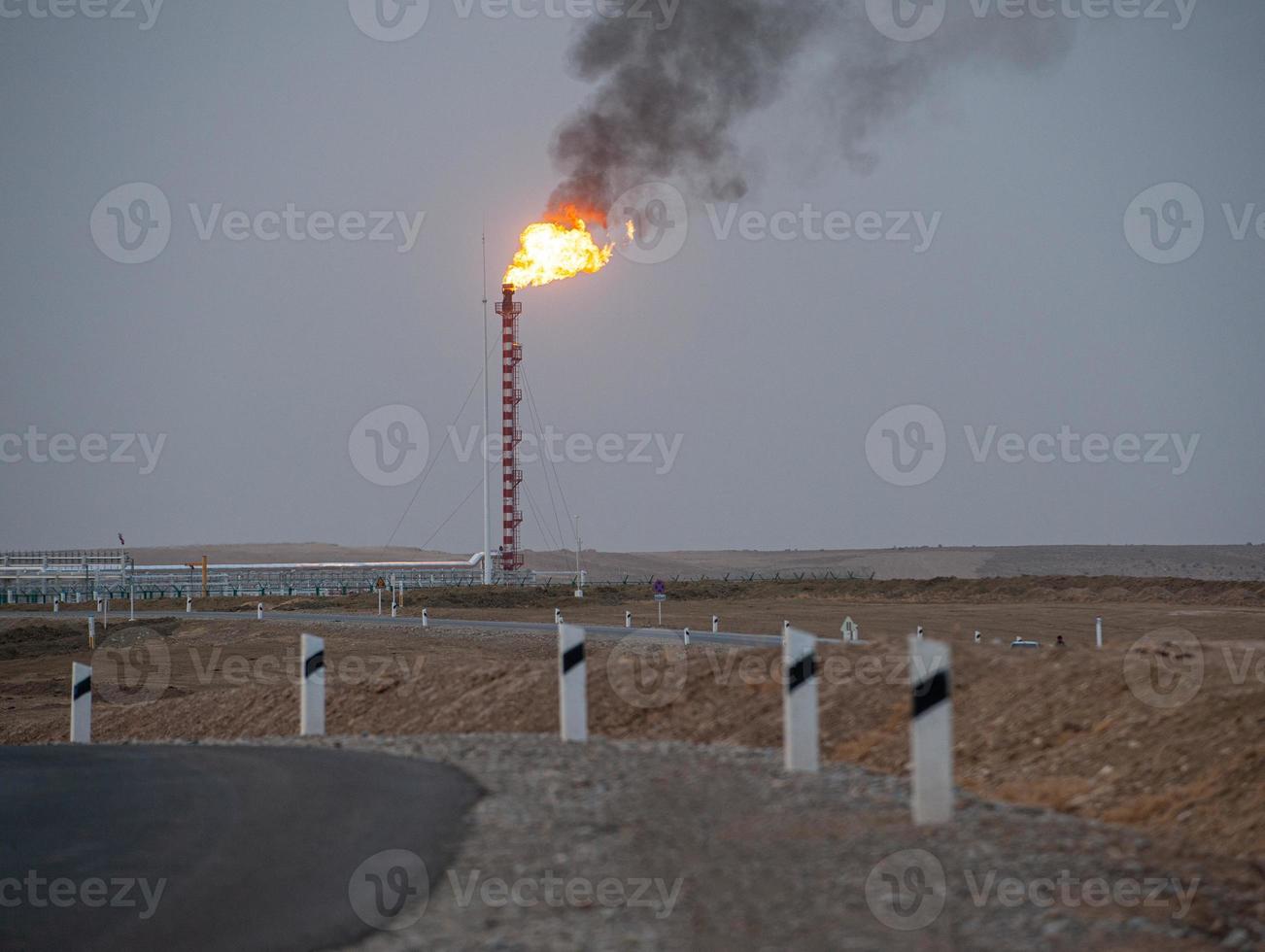 A beautiful shot of the evening highway and burning roof of the construction of the factory in the background photo