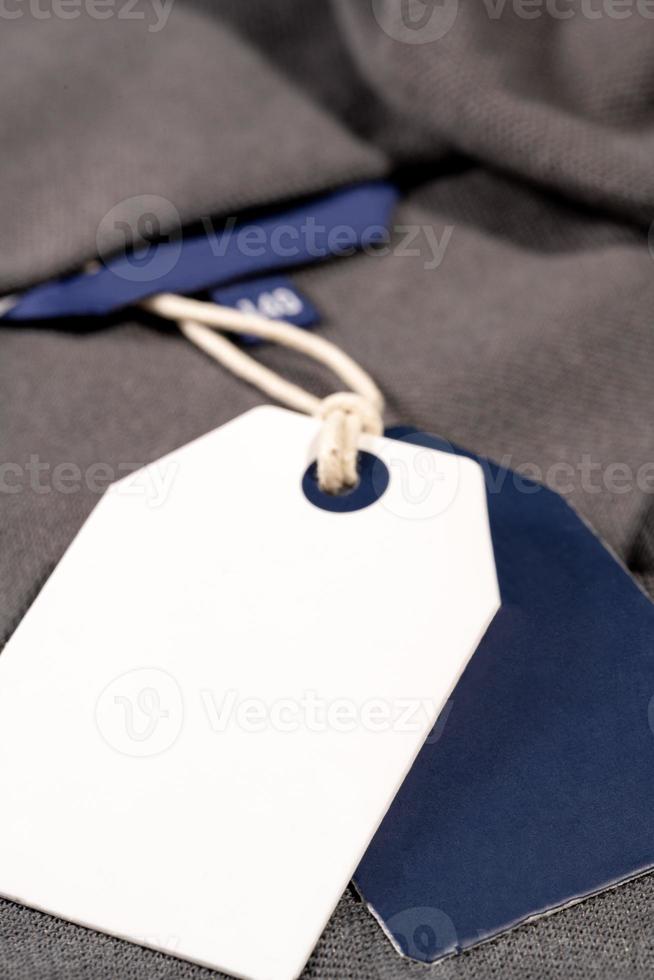 A vertical closeup shot of white blue tags on a string on a cloth with a blank blue tag on the neck photo