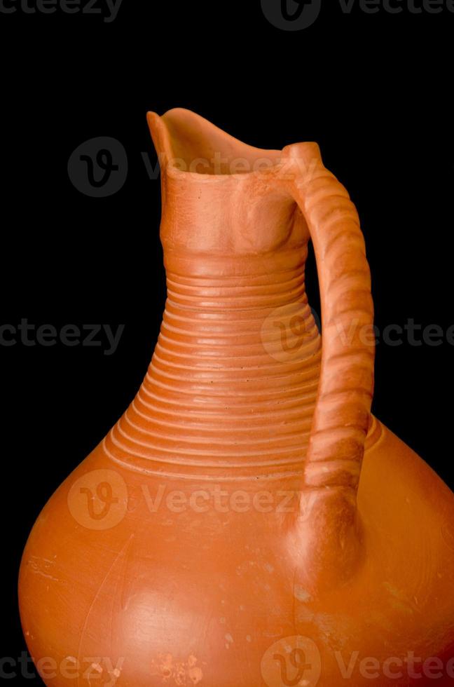 A brown clay jug isolated on a black background photo