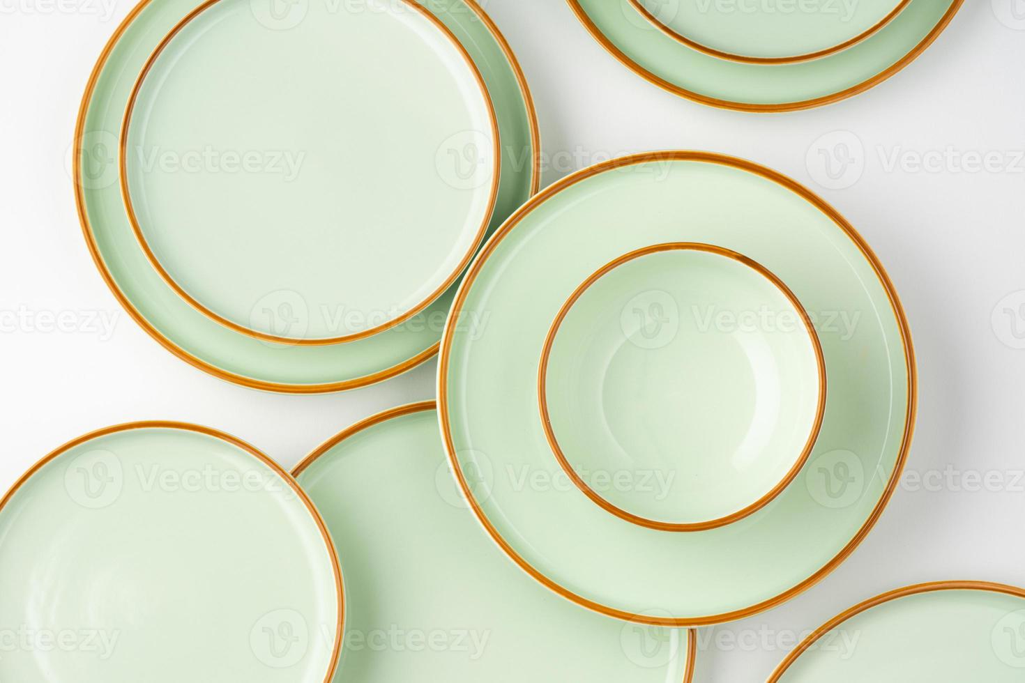 A set of pastel green ceramic tableware with orange outlines. Top view photo