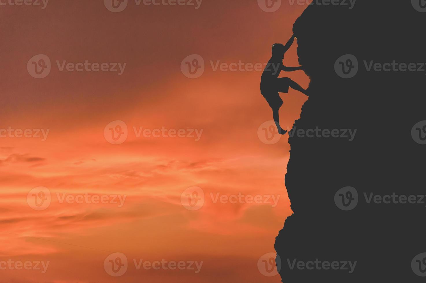 silhouette of a business woman with flags on top of a mountain above sky and sunlight photo