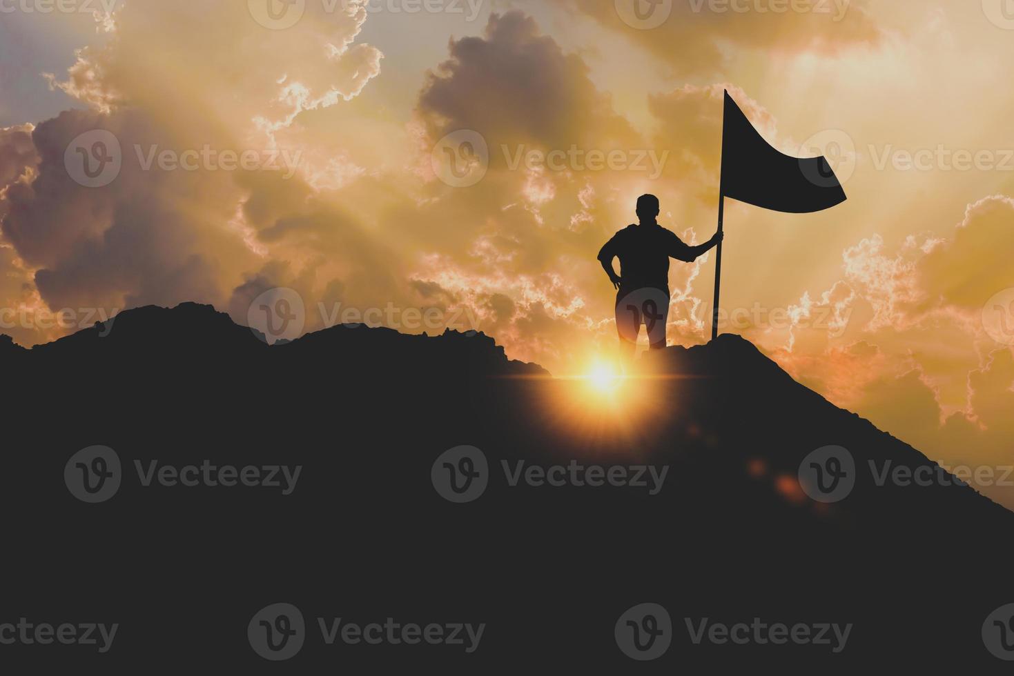 silhouette of a business woman with flags on top of a mountain above sky and sunlight photo