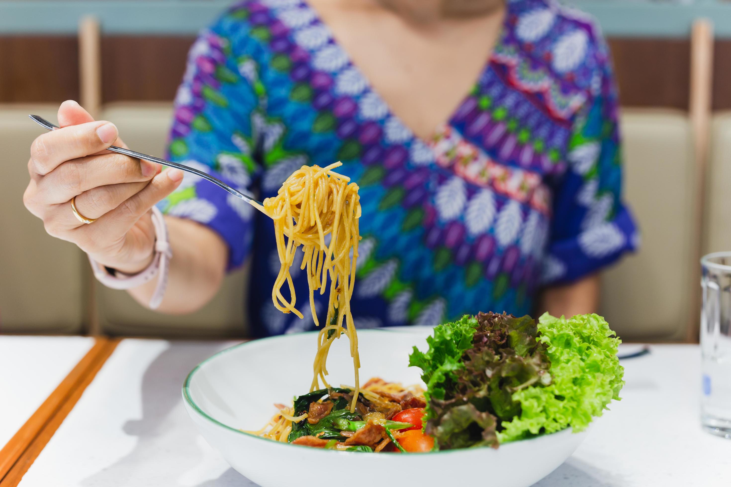 Hand holding fork eating spaghetti in restaurant. 13331870 Stock Photo at Vecteezy