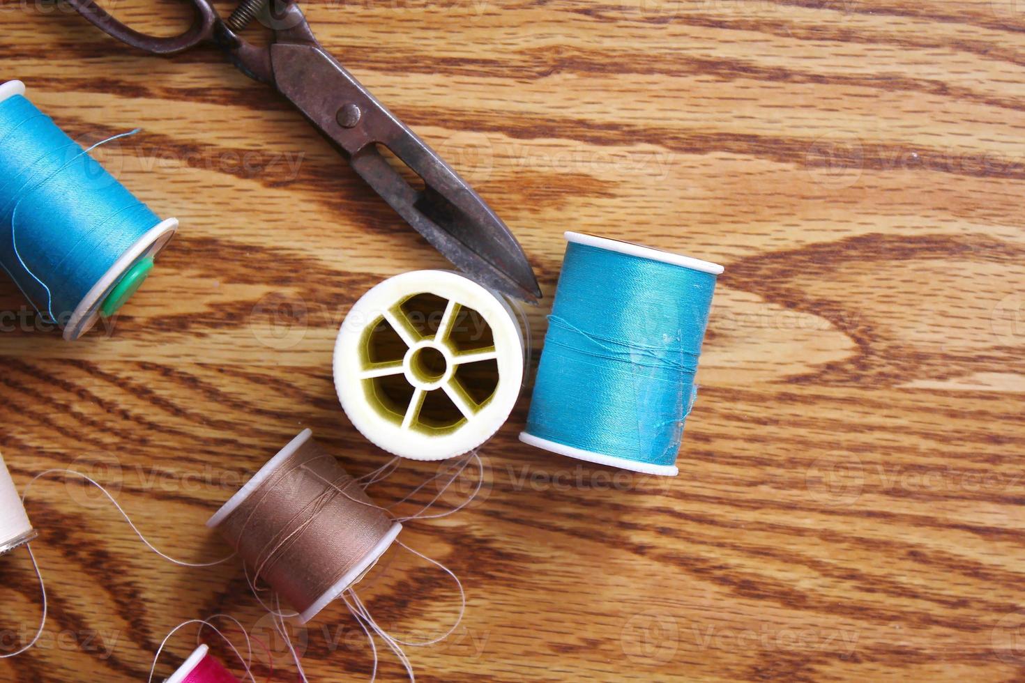 Multicolored threads and old scissors scattered on a wooden table, retro scissors, flat lay, copy space. photo