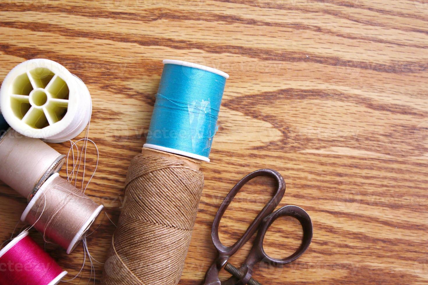 Multicolored threads and old scissors scattered on a wooden table, retro scissors, flat lay, copy space. photo
