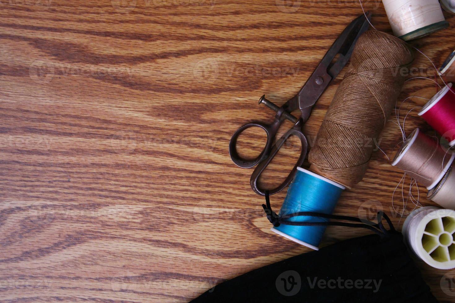 Multicolored threads and old scissors scattered on a wooden table, retro scissors, flat lay, copy space. photo