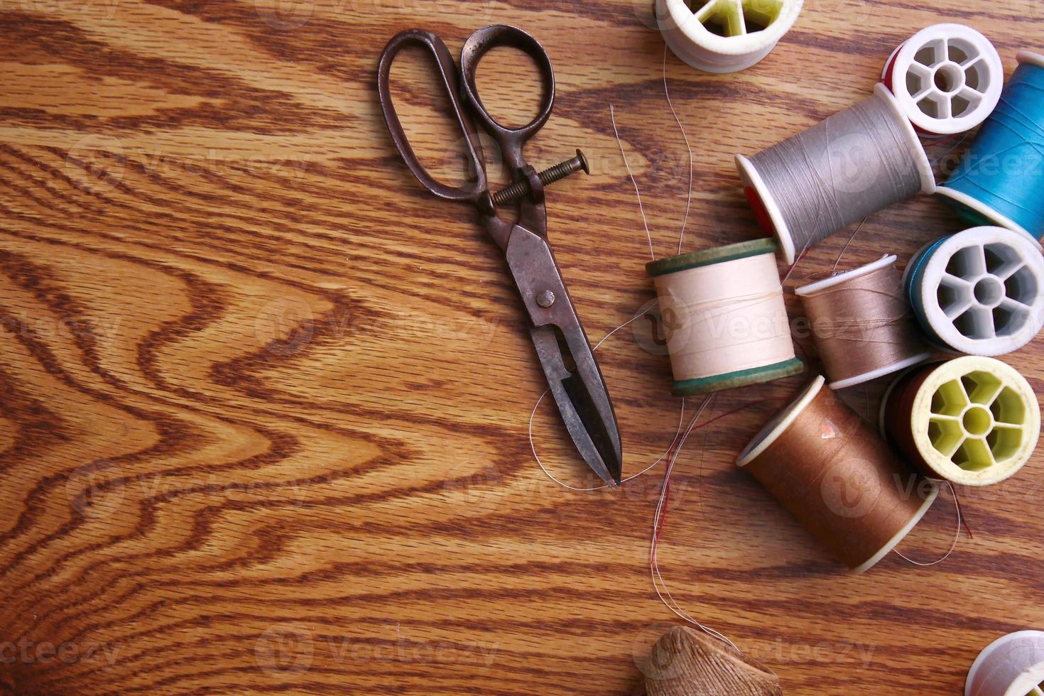 Multicolored threads and old scissors scattered on a wooden table, retro scissors, flat lay, copy space. photo
