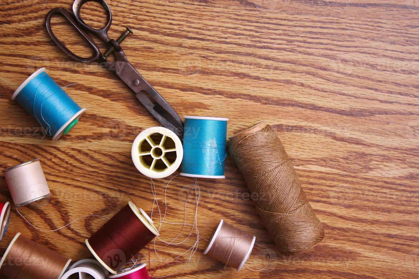 Multicolored threads and old scissors scattered on a wooden table, retro scissors, flat lay, copy space. photo