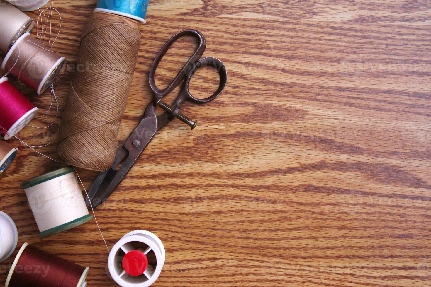 Multicolored threads and old scissors scattered on a wooden table, retro scissors, flat lay, copy space. photo