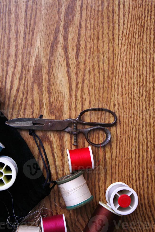 Multicolored threads and old scissors scattered on a wooden table, retro scissors, flat lay, copy space. photo