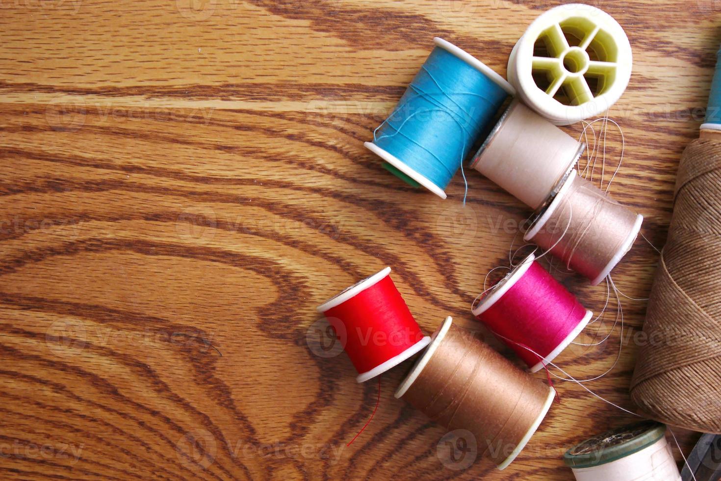 Multicolored threads and old scissors scattered on a wooden table, retro scissors, flat lay, copy space. photo