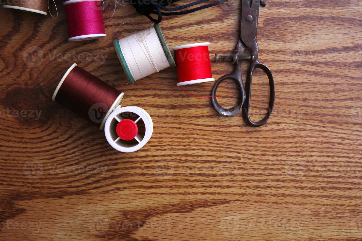 Multicolored threads and old scissors scattered on a wooden table, retro scissors, flat lay, copy space. photo