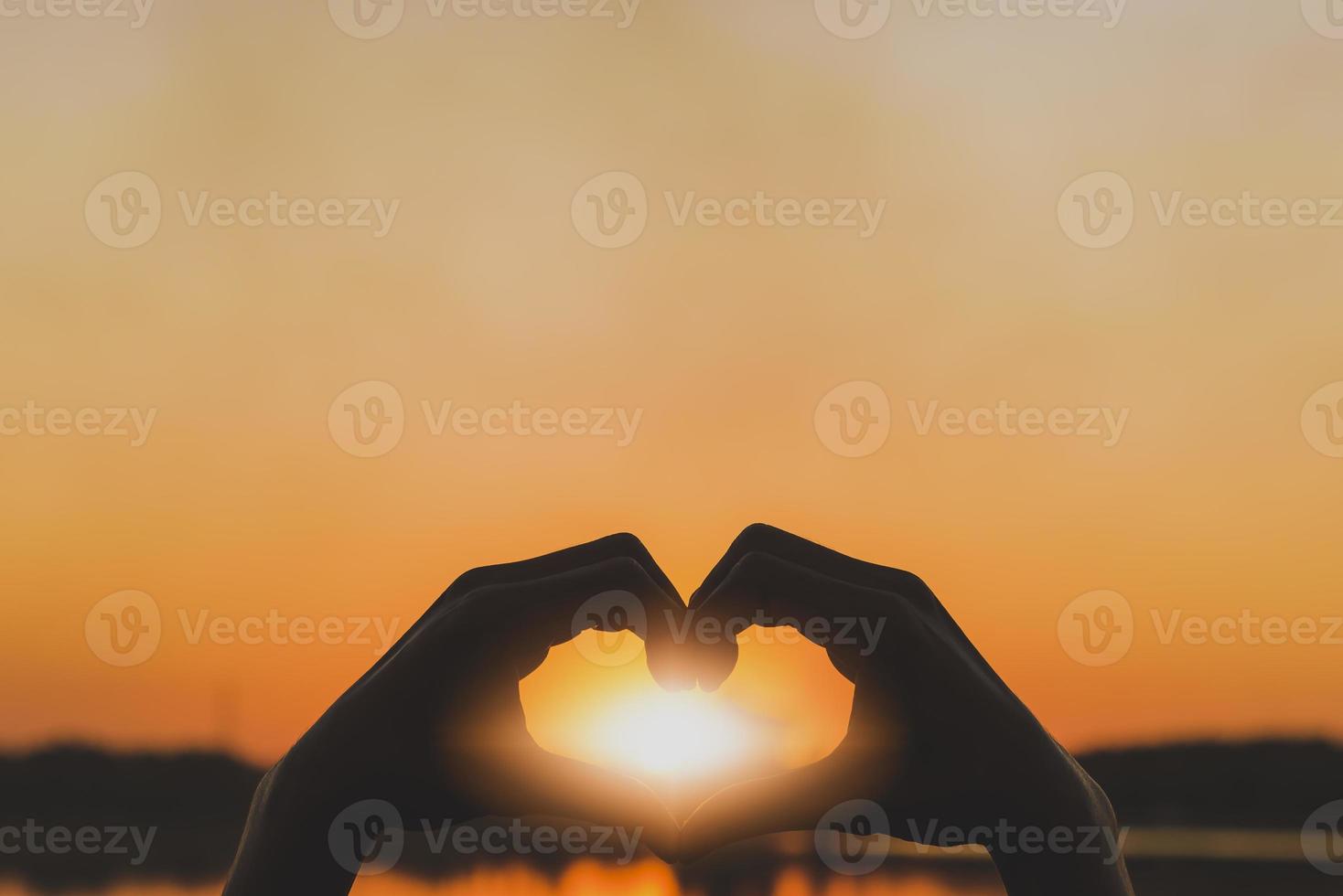 Silhouette love symbol heart symbol hand in the evening sunset. photo