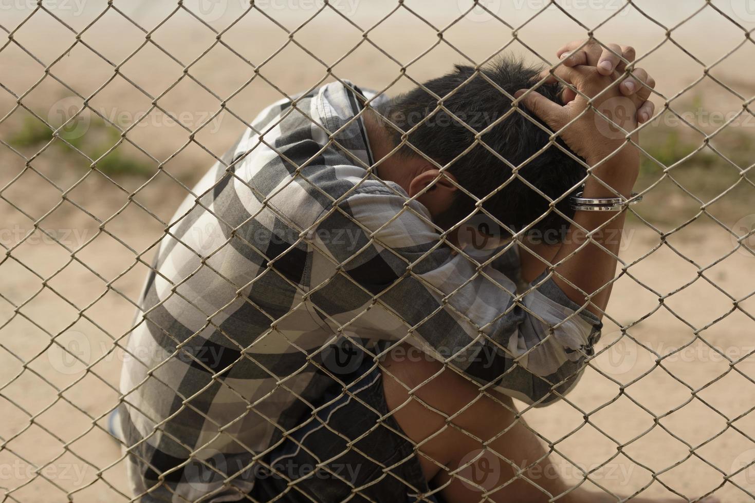 close-up photo of hands in prison steel mesh handle Handles the steel mesh cage, lacks independence.