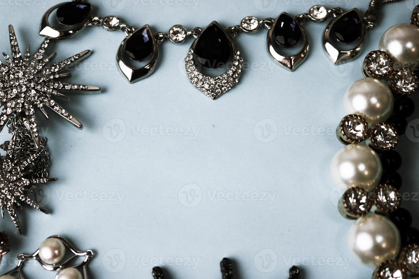 hermosas y preciosas joyas brillantes, joyas glamorosas de moda, collares, aretes, anillos, cadenas, broches con perlas y diamantes sobre un fondo azul. endecha plana, vista superior, lugar de copia foto