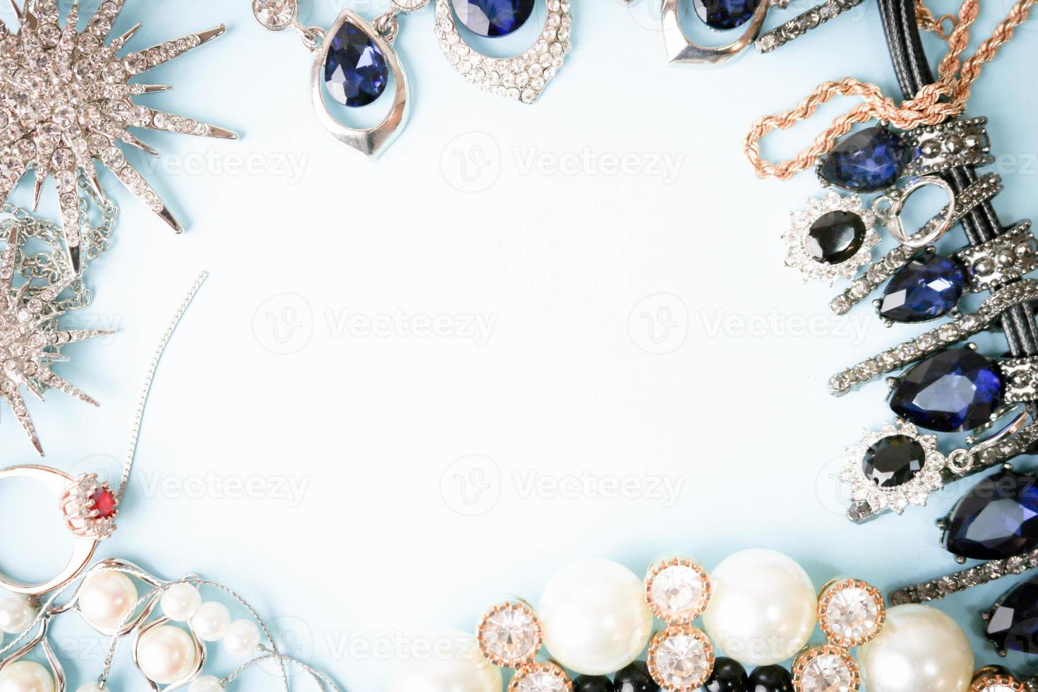 hermosas y preciosas joyas brillantes, joyas glamorosas de moda, collares, aretes, anillos, cadenas, broches con perlas y diamantes sobre un fondo azul. endecha plana, vista superior, lugar de copia foto