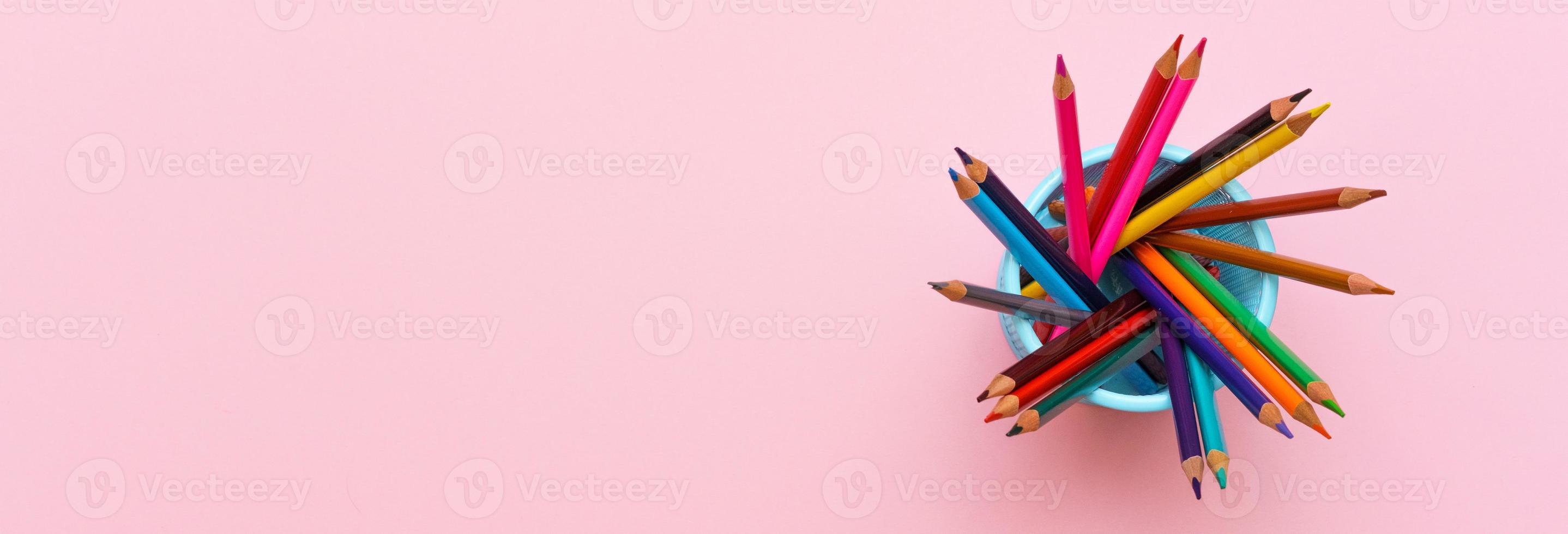 Colored wooden pencils on pink background, education concept. photo