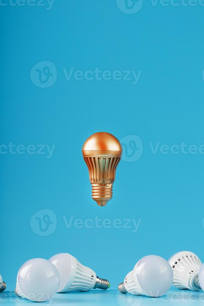 The Golden light bulb rises and hovers above the surroundings of ordinary light bulbs. photo