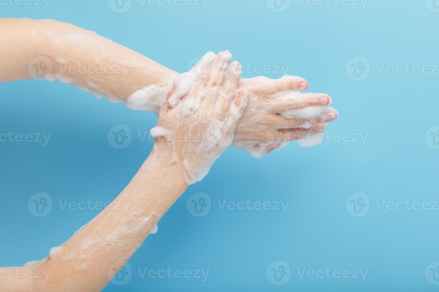 Children's hands in soap suds, on a blue background, top view. photo