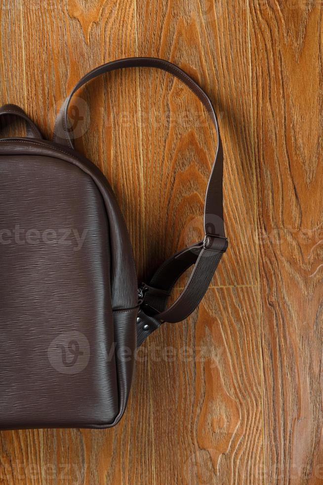 Backpack made of brown genuine leather on a wooden background. photo