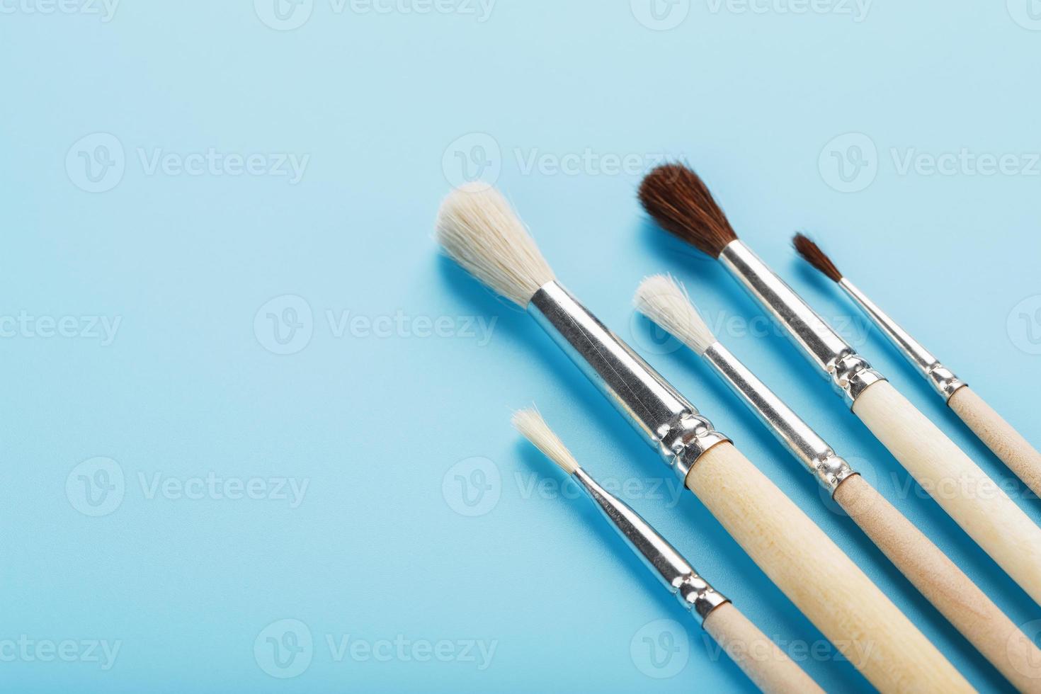 Brushes for drawing with paints made of natural wood and wool on a blue background. photo