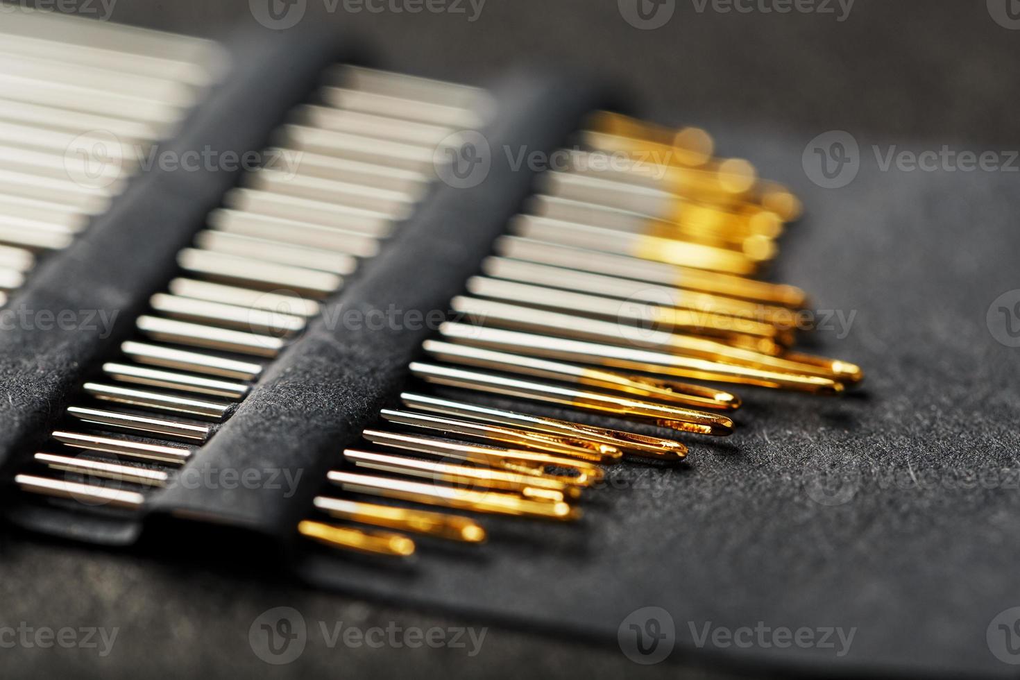 Set of Gold needles on a black background in a row. photo