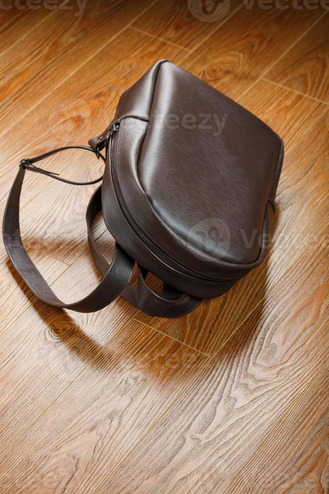 Backpack made of brown genuine leather on a wooden background. photo