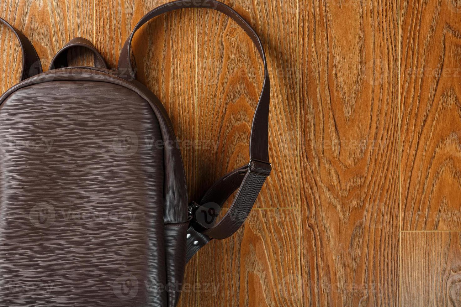 Backpack made of brown genuine leather on a wooden background. photo