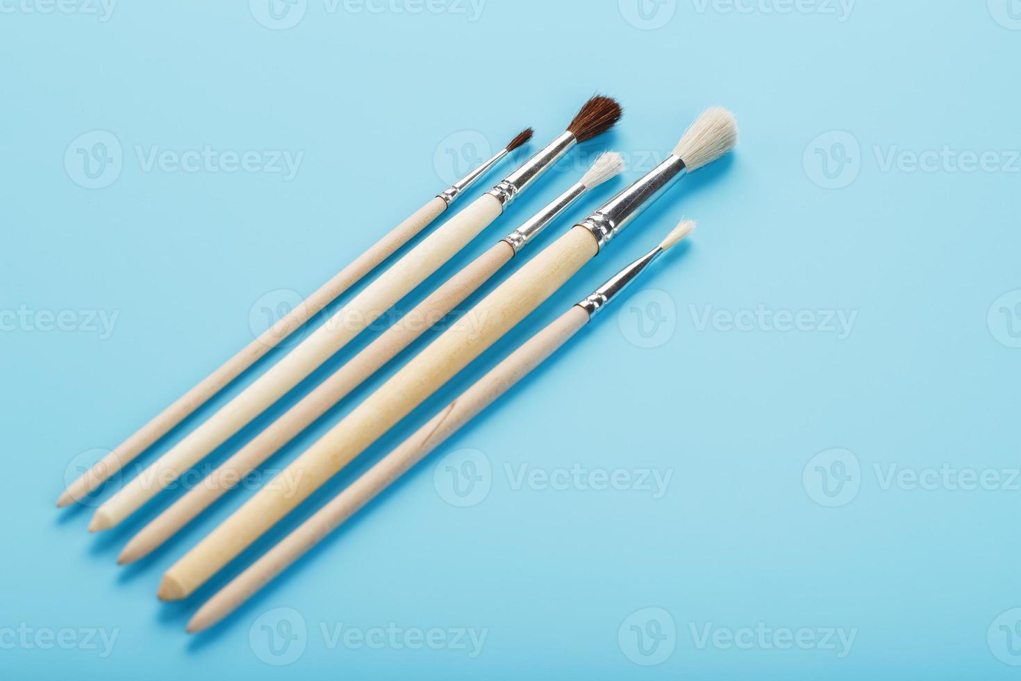 Brushes for drawing with paints made of natural wood and wool on a blue background. photo