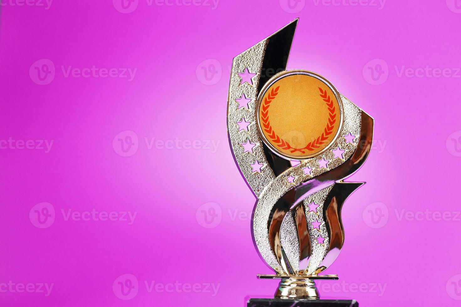 Superprize statuette made of gold on a pink background. photo