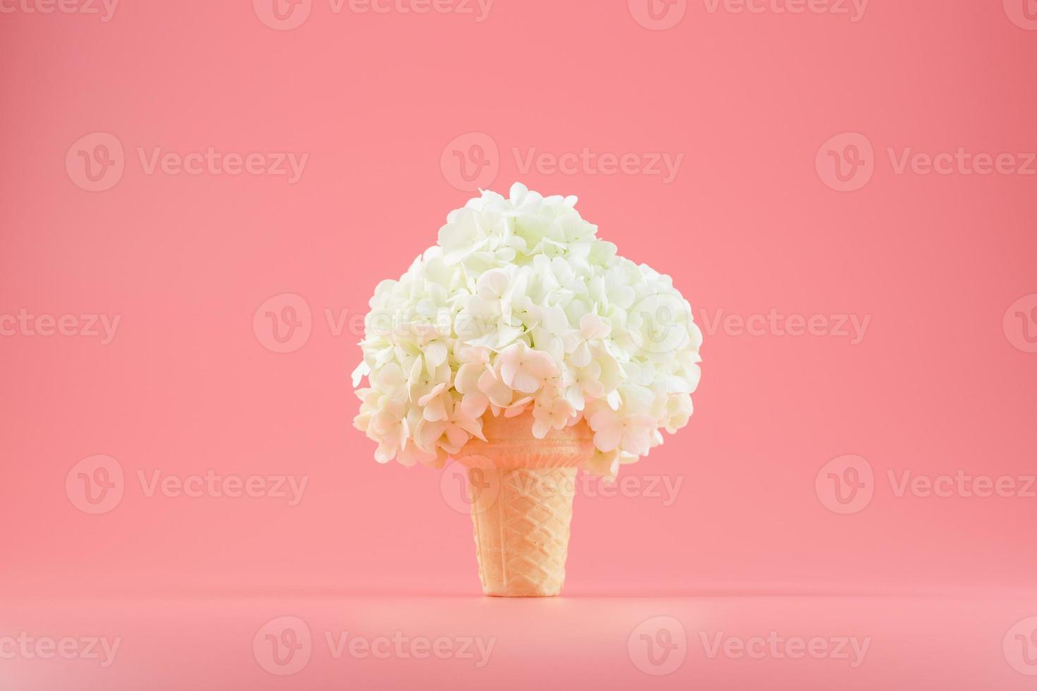 un ramo de flores blancas en un cono de helado sobre un fondo rosa. foto