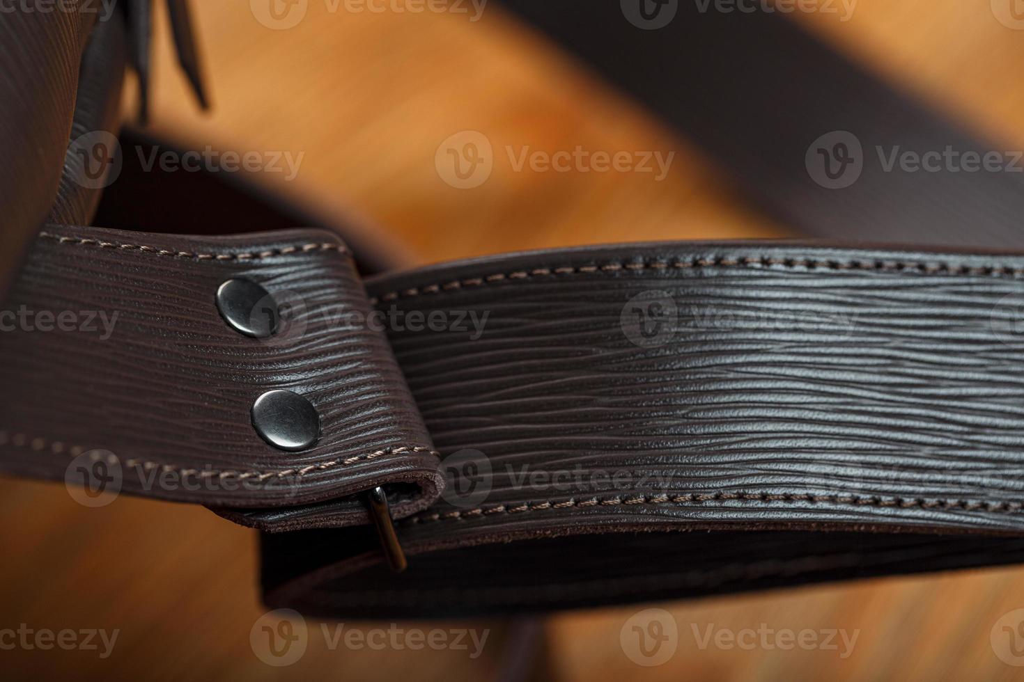 Close-up elements and details of the Backpack made of brown genuine leather on a wooden background. photo