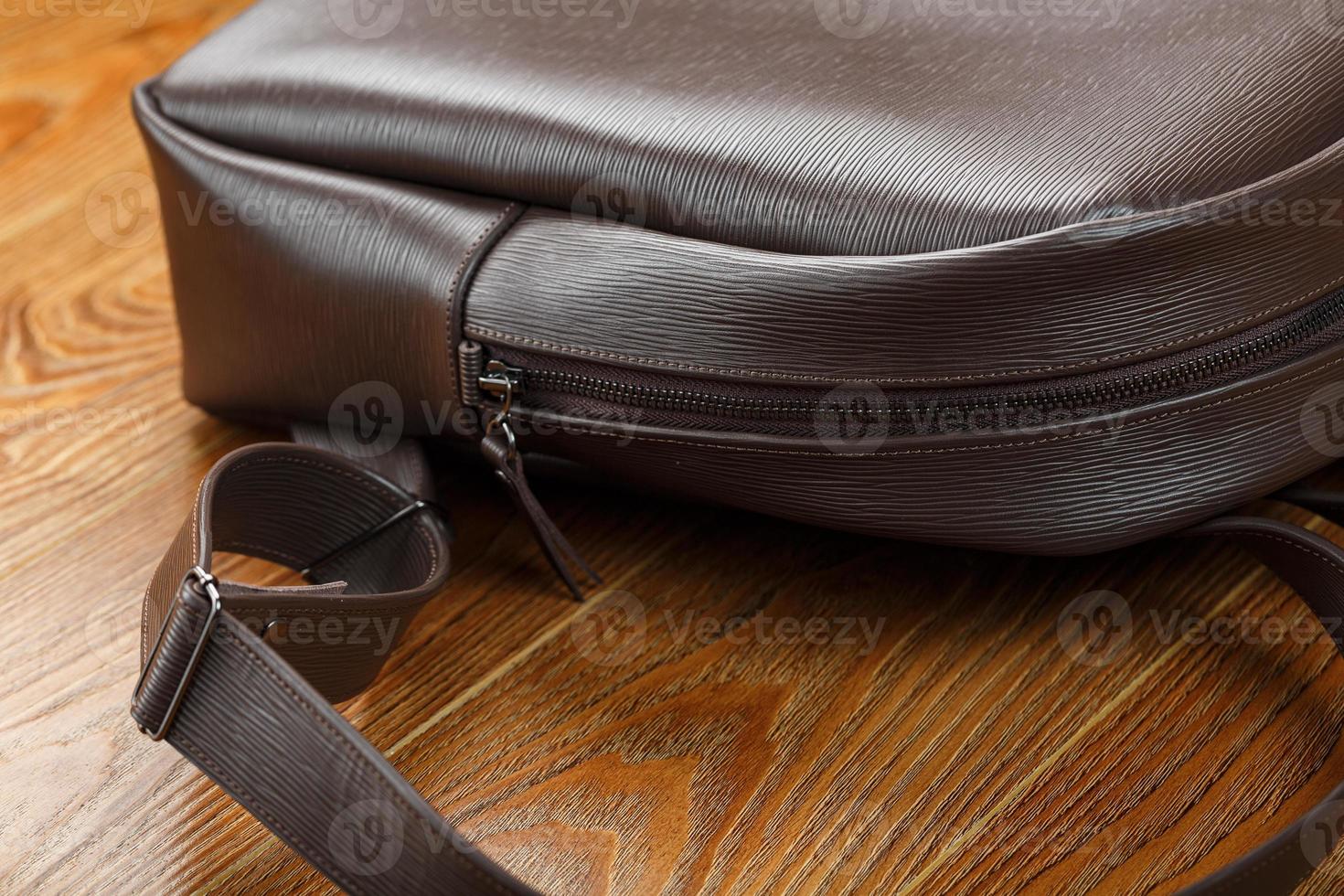 Close-up elements and details of the Backpack made of brown genuine leather on a wooden background. photo