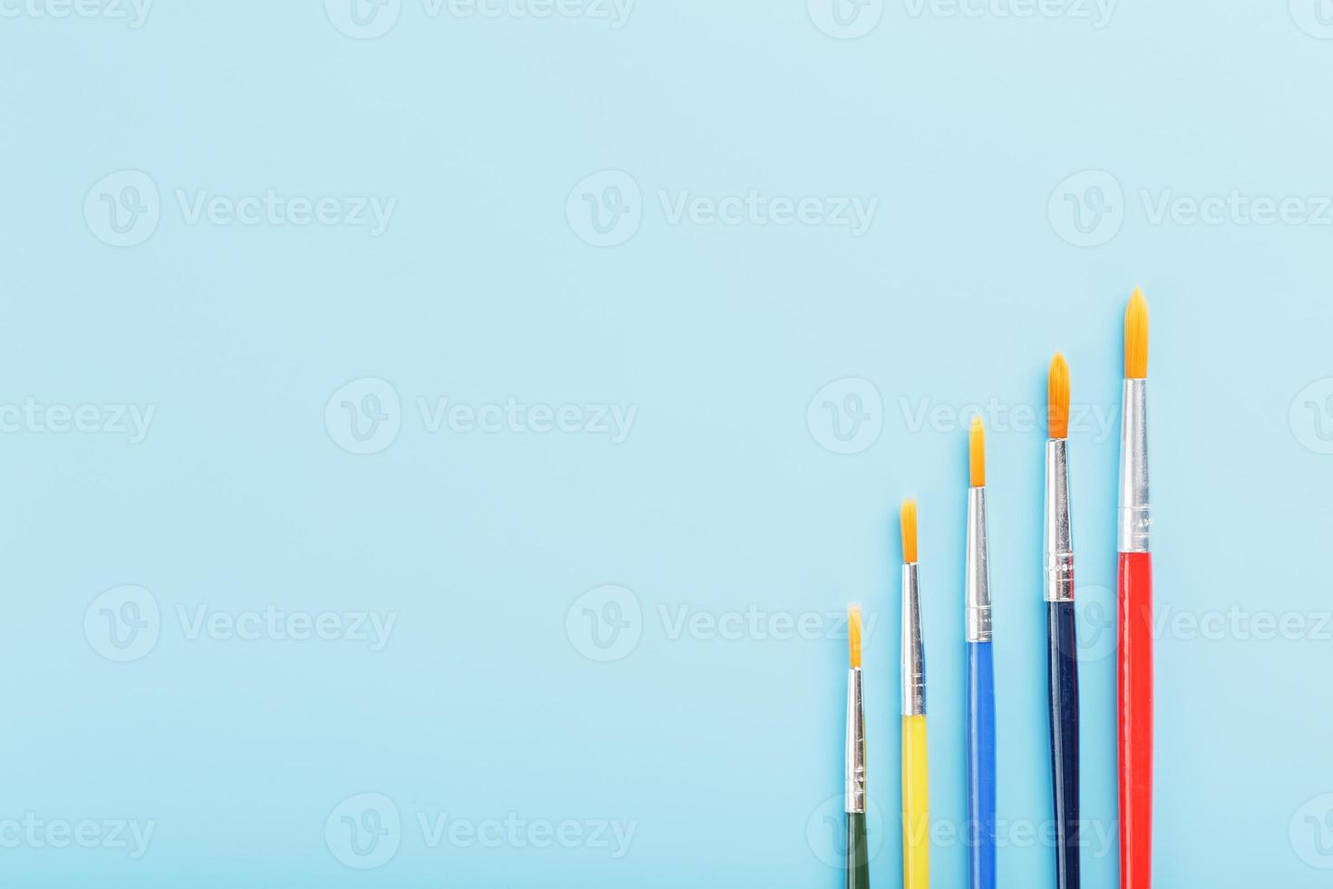 Multi-colored paint Brushes on a blue background. photo