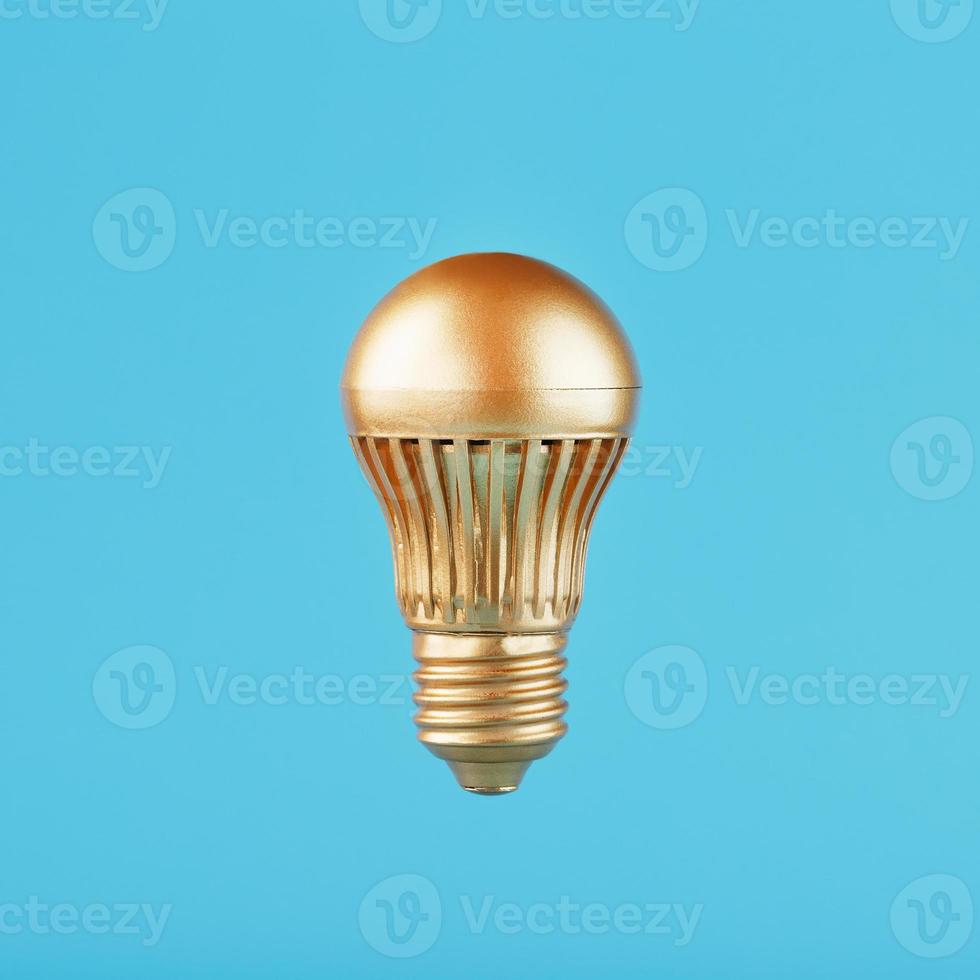 una lámpara led dorada se cierne sobre un fondo azul. concepto de una idea con minimalismo. foto