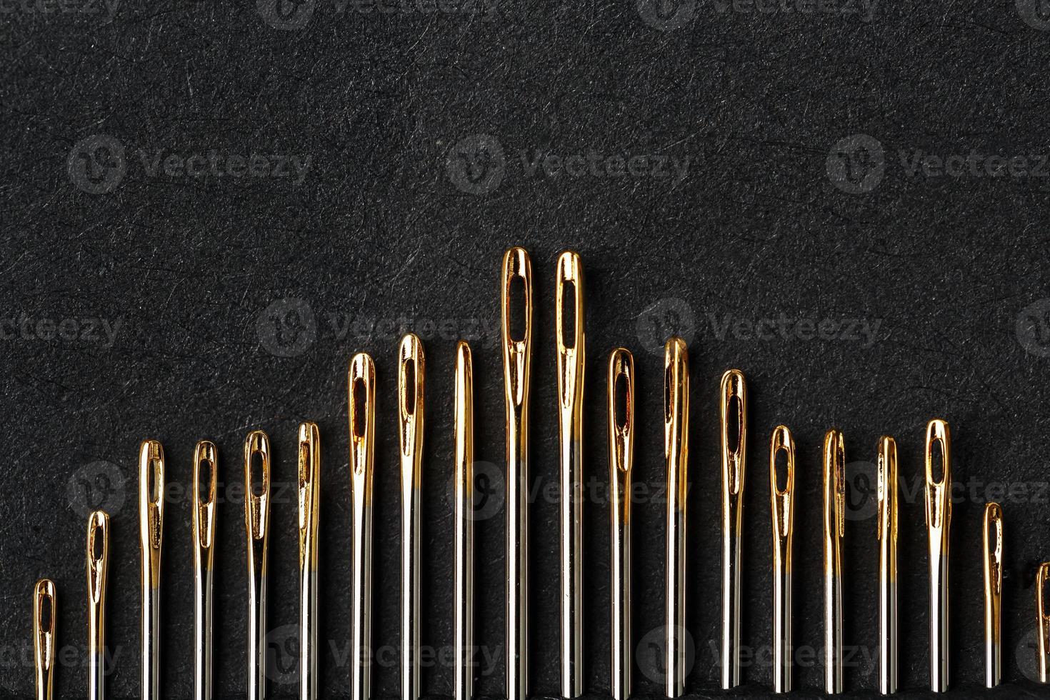 Set of Gold needles on a black background in a row. photo