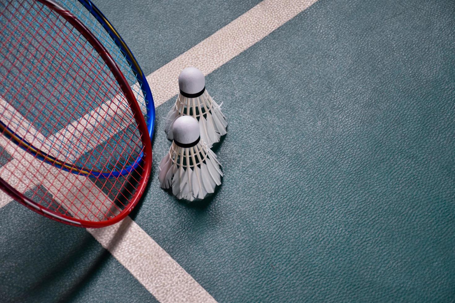 Cream white badminton shuttlecock and racket on floor in indoor badminton court, copy space, soft and selective focus on shuttlecocks. photo