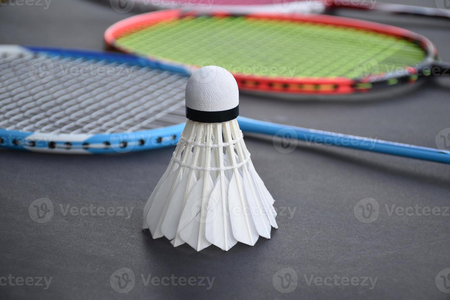 Cream white badminton shuttlecock and racket on floor in indoor badminton court, copy space, soft and selective focus on shuttlecocks. photo