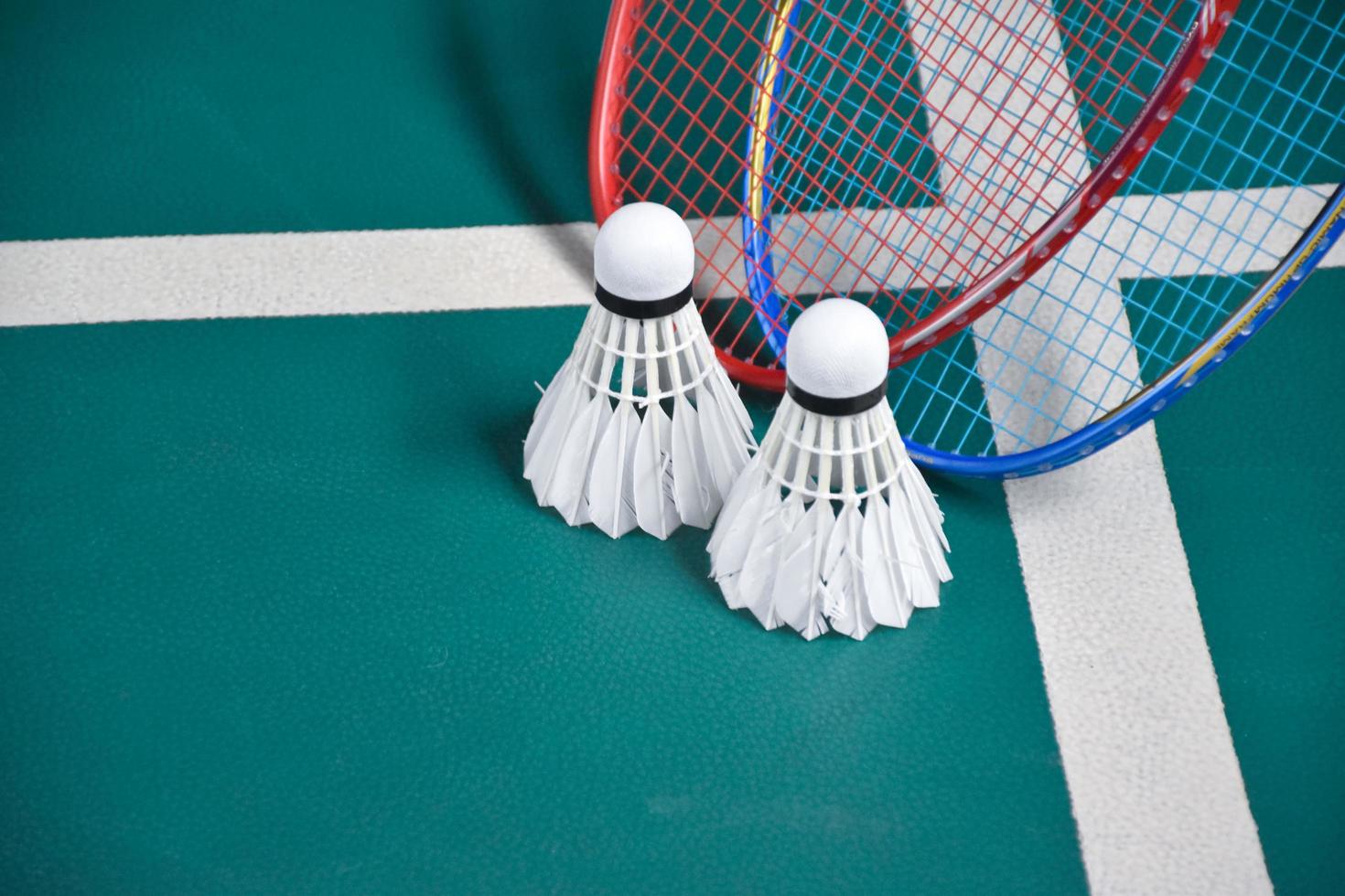 Cream white badminton shuttlecock and racket on floor in indoor badminton court, copy space, soft and selective focus on shuttlecocks. photo