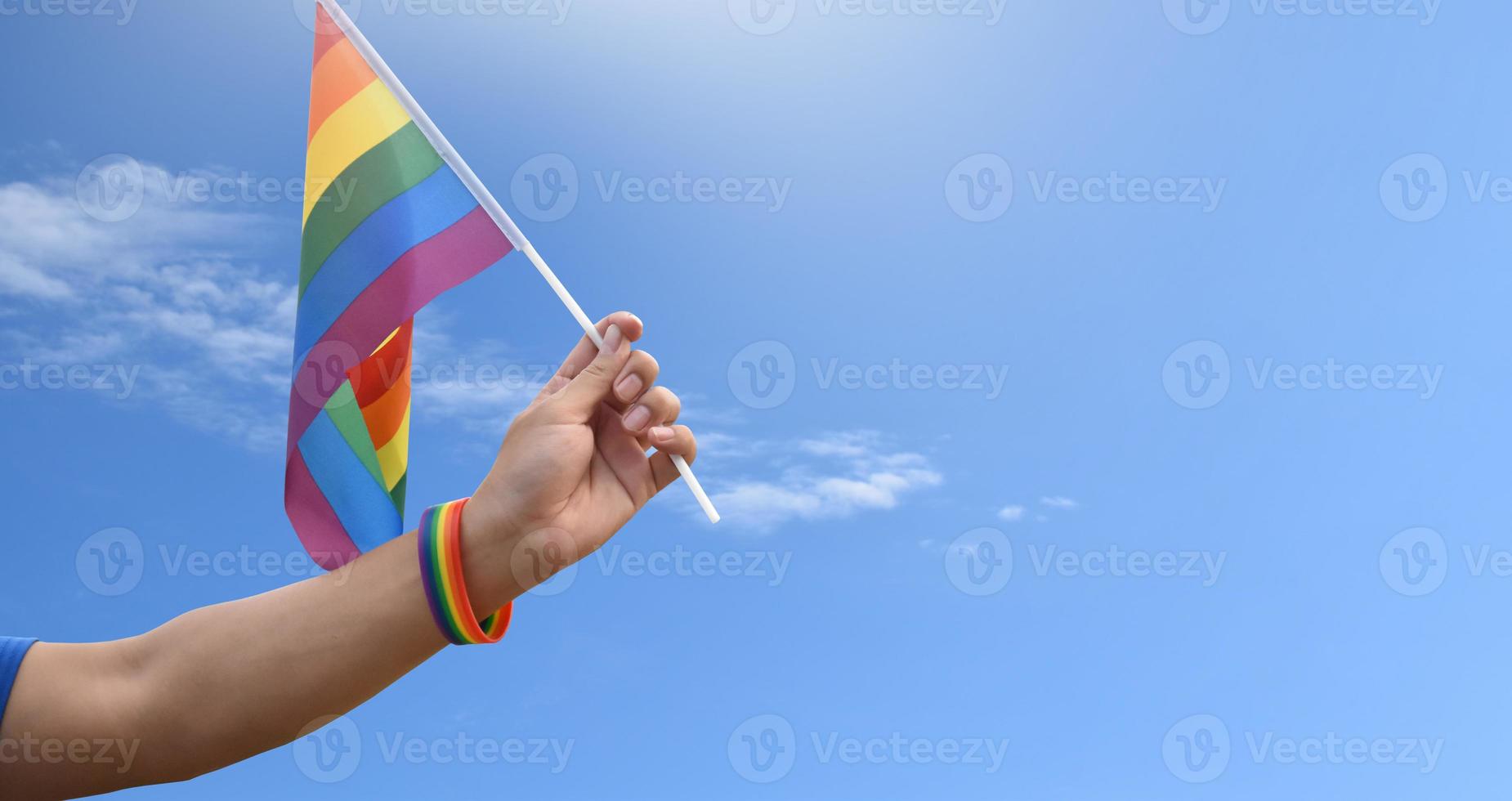 Rainbow flag and wristbands holding in hands, soft and selective focus, concept for lgbtq genders celebrations and calling all people to respect human rights in pride month around the world. photo