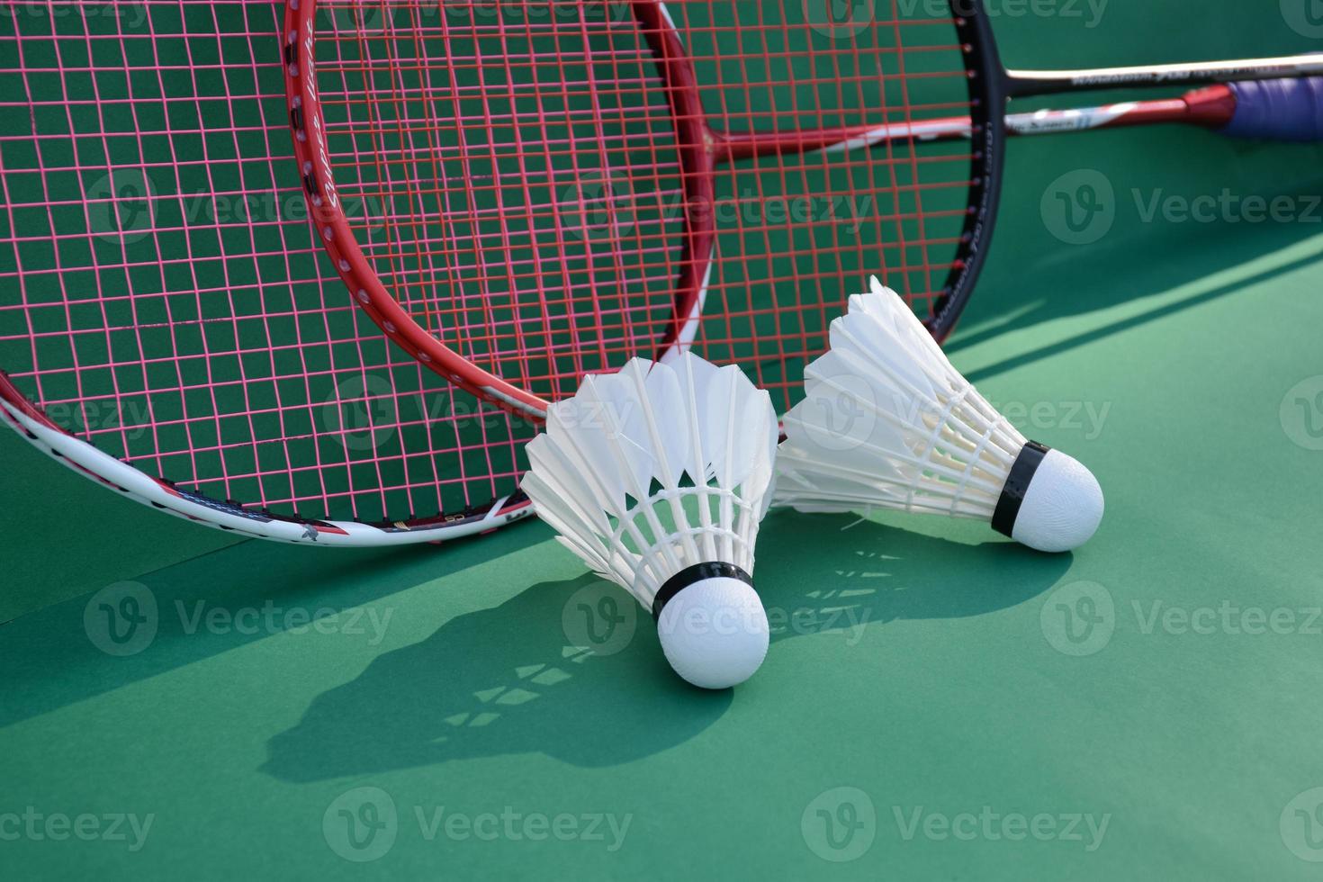 Cream white badminton shuttlecock and racket on floor in indoor badminton court, copy space, soft and selective focus on shuttlecocks. photo