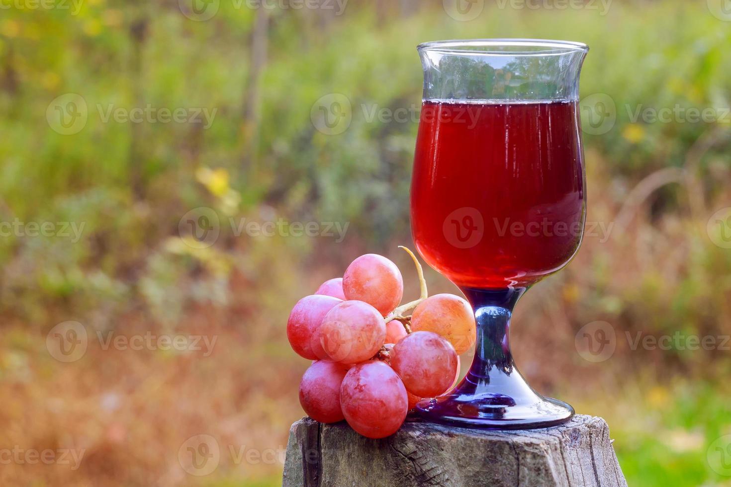 Red wine glass and bunch of grapes on wooden table photo