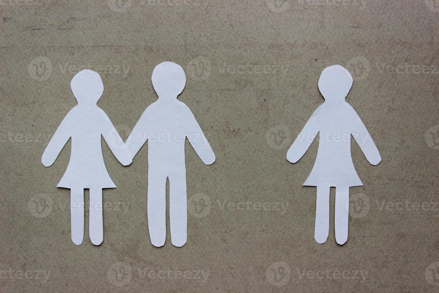 Silhouettes of people cut from paper. Couple holding hands and next to a lonely girl. The concept of relationships, love, jealousy, loneliness, treason photo