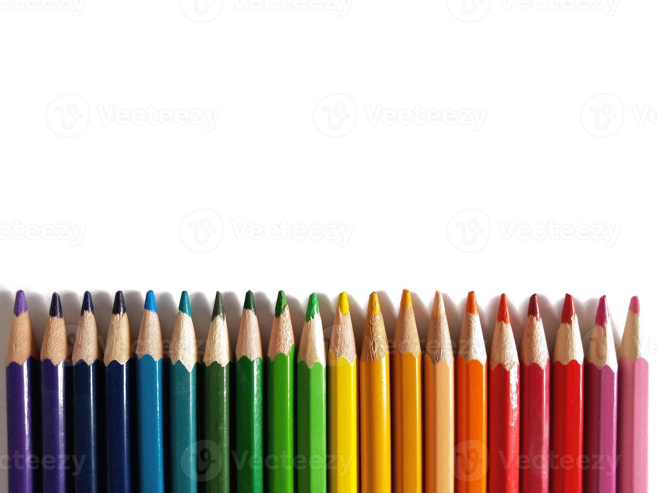 colored pencils for drawing arranged by the color of the rainbow on a white background photo